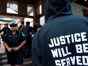A man protesting the shooting death of Sammy Yatim by Toronto police confronts officers outside police headquarters during a public protest in Toronto on Wednesday, August 13, 2013. THE CANADIAN PRESS/Galit Rodan
