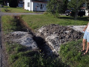 Charles Akins of Longfellow Avenue inspects a gravel road serving a solar farm which remains on property north of 2018  Longfellow Ave. September 4, 2013.  Only a small portion of the gravel road covering the roadside ditch, shown, was removed according to Akins. (NICK BRANCACCIO/The Windsor Star)