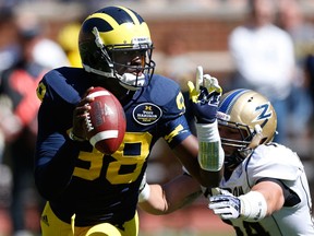 Michigan quarterback Devin Gardner scrambles away from Akron's Nick Rossi during the fourth quarter at Michigan Stadium Saturday in Ann Arbor. (Photo by Gregory Shamus/Getty Images)