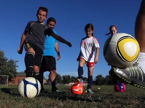 Tecumseh Soccer Club coaches  J.J. Dowhan and Ryan Mendonca, right, demonstrate and watch the footwork of players Jaden Macari, 10, left, Mia Macari, 8, and Anaya Macari, 13, at Green Acres Park, September 18, 2013. (NICK BRANCACCIO/The Windsor Star)