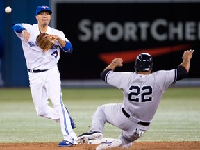 Toronto's Ryan Goins, left, turns a double play over New York's Vernon Wells during the fourth inning Wednesday in Toronto. (THE CANADIAN PRESS/Mark Blinch)