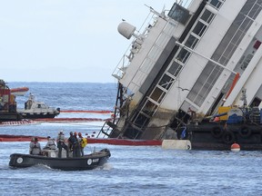 The Costa Concordia cruise ship wreck begins to emerge from water on September 16, 2013 near the harbour of Giglio Porto. Salvage workers attempt to raise the cruise ship today in the largest and most expensive maritime salvage operation in history, so-called "parbuckling", to rotated the ship by a series of cables and hydraulic machines. Thirty-two people died when the ship, with 4,200 passengers onboard, hit rocks and ran aground off the island of Giglio on January 2012. AFP PHOTO / ANDREAS SOLARO