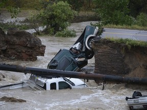 Three vehicles crashed into a creek after the road washed out from beneath them near Dillon Rd. and 287 in Broomfield Colo., Thursday, Sept. 12, 2013 in heavy flooding. Three people were rescued. (AP Photo By Andy Cross/The Denver Post)