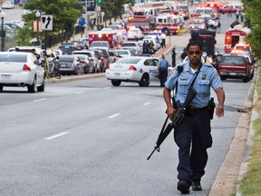 A Metropolitan Police Department officer walks near the Washington Navy Yard after at least one gunman launched an attack inside the Washington Navy Yard, spraying gunfire on office workers in the cafeteria and in the hallways at the heavily secured military installation in the heart of the nation's capital, in Washington, on Monday, Sept. 16, 2013. (AP Photo/Jacquelyn Martin)