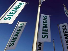 In this Jan. 23, 2013 file photo, flags of German engineering conglomerate Siemens AG flutter before the annual shareholder meeting in Munich, southern Germany. German news agency dpa reported Sunday, Sept. 29, 2013, that the company wants to cut 5,000 jobs in Germany and another 10,000 jobs abroad. (AP Photo/Matthias Schrader, File)