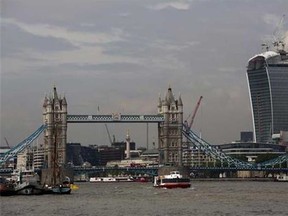 The 37-storey skyscraper at 20 Fenchurch Street, right, which is still under construction is seen near Tower Bridge in the City of London, Tuesday, Sept. 3, 2013. Developers for an unfinished skyscraper in central London say they are investigating the way the building reflects bright sunlight _ after claims that the intense glare melted parts of a car parked nearby. The companies behind the skyscraper, nicknamed the “Walkie-Talkie” because of its curved shape, are responding to complaints from the owner of a Jaguar who told the BBC that the mirror, panels and the Jaguar badge had all melted from the concentrated heat of sunlight reflected from the building. (AP Photo/Matt Dunham)