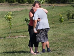 A woman consoles a man at the scene of a fatal ATV accident Tues. Sept. 10, 2013, on the South Middle Rd. just west of County Rd. 27. The accident occurred several hundred metres from the roadway. (DAN JANISSE/The Windsor Star)