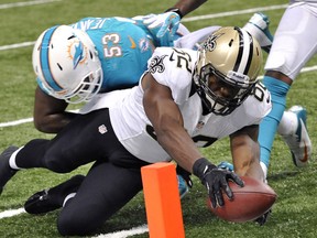 New Orleans Saints tight end Benjamin Watson, right, reaches over the pylon to score a touchdown ahead of Miami's Jelani Jenkins in New Orleans Monday. (AP Photo/Bill Feig)