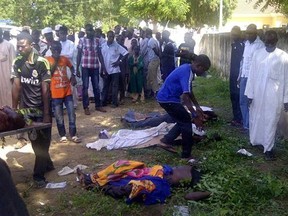 EDS NOTE GRAPHIC CONTENT : In this image taken with a mobile phone, rescue workers and family members gather to identify the shrouded bodies of students killed following an attack by Islamist extremist on an agricultural college in Gujba, Nigeria, Sunday, Sept. 29, 2013, Suspected Islamic extremists attacked the Yobe State College of Agriculture early Sunday, gunning down students as they slept in dormitories and torching classrooms, leaving some 50 students dead in the attack according to college Provost Molima Idi Mato. The attack is seen as part of an ongoing Islamic uprising in northeastern Nigeria prosecuted by Boko Haram militants in their declared quest to install an Islamic state. (AP Photo)