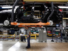 In this 2013 file photo, Jeff Caldwell, 29, right, a chassis assembly line supervisor, checks a vehicle on the assembly line at the Chrysler Jefferson North Assembly plant in Detroit. (AP Photo/Paul Sancya, File)