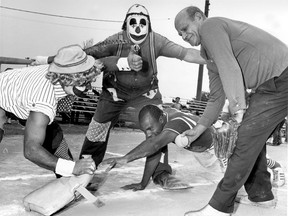 "Fluffy" the clown calls base runner Ronald Jones 'out' as he pulls the base out of his reach, but "Tubby" the clown passes a more honest decision. Eight zany fire fighter clowns acted as officials in a softball game between the regular fire fighters baseball team and the "oldtimers," team on Sept. 3, 1968. From left: Ronald Maire, James Meyer, Ronald Jones, oldtimer, Vincent Wilds. The action was part of the annual Fire Fighters Field Day held during the weekend. (The Windsor Star Staff Photo)