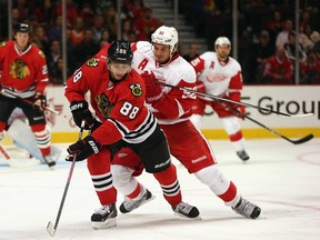 Patrick Kane, left, of the Chicago Blackhawks controls the puck under pressure from Jonathan Ericsson of the Detroit Red Wings during an exhibition game at United Center on September 17, 2013 in Chicago. ( Jonathan Daniel/Getty Images)
