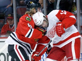 Chicago's Mike Kostka, left, and Detroit's Patrick Eaves battle for the puck behind the Blackhawks' net in a pre-season hockey game Tuesday, Sept. 17, 2013, in Chicago. (AP Photo/Charlie Arbogast)