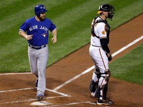 Toronto's Adam Lind, left, scores a run in front of Baltimore catcher Matt Wieters on a single by Ryan Goins during the second inning Tuesday, Sept. 24, 2013, in Baltimore. (AP Photo/Patrick Semansky)