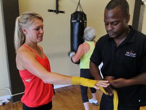 Kelly Steele has her hands taped before a boxing workout with Cedric Benn, right,  of Refine Fitness. (NICK BRANCACCIO / The Windsor Star)