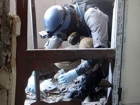 A member of a UN investigation team takes samples from the ground in the Damascus countryside of Zamalka, Syria, on Aug. 29, 3013. (Associated Press)