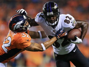 Baltimore's Torrey Smith, right, runs with the ball  in front of Denver's Tony Carter at Sports Authority Field at Mile High on September 5, 2013 in Denver. (Doug Pensinger/Getty Images)