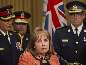 Community Safety Minister Madeleine Meilleur (centre) attends a news conference to announce  it will be up to local police forces to decide whether to equip their officers with stun guns, and it will be up to those forces to pay for them. THE CANADIAN PRESS/Chris Young