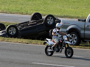 A motorcyclist slows down to look at a single vehicle roll over accident on E.C. Row near Lauzon Parkway in Windsor on Wednesday, September 11, 2013.           (TYLER BROWNBRIDGE/The Windsor Star)