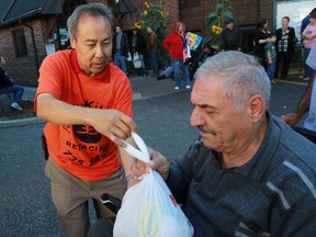 Andy Jun, owner of ReNu Kitchen Refacing in Tecumseh, hands out a turkey to Azad Bafdasar at the Downtown Mission, Saturday, Oct. 12, 2013.  Jun purchased turkeys and hams and a portion of the donated canned goods to hand out to those in need for Thanksgiving.  (DAX MELMER/The Windsor Star)