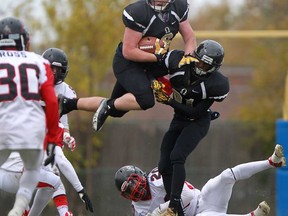 AKO tight end, Kyle Moynahan, centre, leaps through the air with the help of teammate, Shayne Rice, for the first down as the AKO Fratmen host the Vancouver Island Raiders in the Canadian Junior Football League semifinal at Windsor Stadium, Saturday, Oct. 26, 2013.  Vancouver Island defeated AKO 50-3.  (DAX MELMER/The Windsor Star)