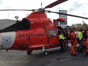 A Coast Guard air crew, from Air Station Detroit, involved with the medevac of a 57-year-old man, transfers the patient to paramedics at Windsor Airport on Oct. 27, 2013. The crew plucked the man off the 730-foot Algoma Enterprise, which was passing through the Pelee Passage in Lake Erie. (U.S. Coast Guard photo by Lt. Jim Cepa)