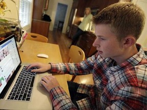 In this Oct. 24, 2013 photo, Mark Risinger, 16, checks his Facebook page on his computer as his mother, Amy Risinger, looks on at their home in Glenview, Ill. The recommendations are bound to prompt eye-rolling and LOLs from many teens but an influential pediatrician's group says unrestricted media use has been linked with violence, cyber-bullying, school woes, obesity, lack of sleep and a host of other problems. (AP Photo/Nam Y. Huh)