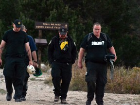 Chaffee County Sheriff's Deputy Kevin Everson, right, and other deputies walk out the Agnes Vaille Falls trail shortly after leaving the scene of a rock slide that killed five people Monday, Sept. 30, 2013, in Chaffee County, Colo. Deputies who reached the area rescued a teenage girl who suffered a broken leg but had to pull back after rocks kept falling from a cliff and a boulder field with rocks estimated at weighing more than 100 tons began shifting. Rescuers were to return to the site Wednesday. (AP Photo/P. Solomon Banda)