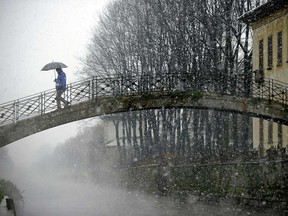 In this file photo, a man crosses a bridge on the Niviglio river under a brief snowstorm on in Robecco sul Naviglio, near Milano in the Lombardy region of northern Italy. (OLIVIER MORIN/AFP/Getty Images)