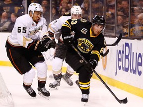 Boston's Brad Marchand, right, shoots the puck around the boards in front of Anaheim's Emerson Etem at TD Garden in Boston. (Photo by Jared Wickerham/Getty Images)
