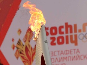 One of the Olympic torches rises in front of a poster with the Sochi 2014 Winter Olympic logo just outside the Red Square in Moscow, on October 7, 2013, during a ceremony to kick off the Sochi 2014 Winter Olympic torch relay across Russia (KIRILL KUDRYAVTSEV/AFP/Getty Images)