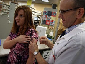 Pharmacist Gary Willard at Ziter Pharmacy on Howard Avenue gives a flu shot to Tanya McIntosh Wednesday October 23, 2013. (NICK BRANCACCIO/The Windsor Star)