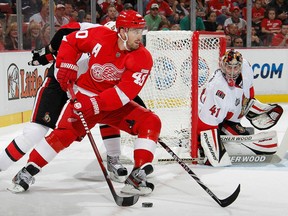 Detroit's Henrik Zetterberg, centre, looks to get a shot off in front of Ottawa goalie Craig Anderson. (Photo by Gregory Shamus/Getty Images)