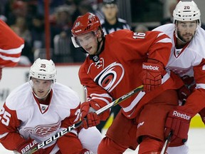 Detroit's Cory Emmerton, left, and Drew Miller, right, check Carolina's Elias Lindholm Friday in Raleigh, N.C. (AP Photo/Gerry Broome)