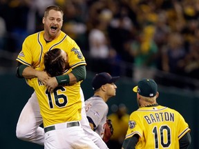 Oakland's Stephen Vogt, left, is lifted up by teammate Josh Reddick as Daric Barton moves in to celebrate Vogt's game-winning hit in the bottom of the ninth inning against the Tigers in Game 2 of the ALDS. (AP Photo/Marcio Jose Sanchez)