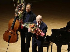 Cellist Yo-Yo Ma, left, and Holocaust survivor George Horner, right, hold flowers as they bow after performing together on stage at Symphony Hall Tuesday, Oct. 22, 2013, in Boston. The 90-year-old pianist made his orchestral debut with Ma, where they played music composed 70 years ago at the Nazi concentration camp where Horner was imprisoned. (AP Photo/Steven Senne)