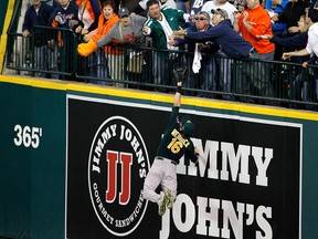 Oakland Athletics right fielder Josh Reddick stretches but is unable to catch a solo home run by Detroit Tigers' Victor Martinez, as fans reach for the ball during the seventh inning of Game 4 of baseball's American League division series in Detroit, Tuesday, Oct. 8, 2013. (AP Photo/Duane Burleson)