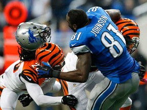 Detroit wide receiver Calvin Johnson, centre, loses his helmet trying to catch a pass while being hit by Cincinnati's George Iloka, right, and Reggie Nelson Sunday, Oct. 20, 2013, in Detroit. (AP Photo/Rick Osentoski)