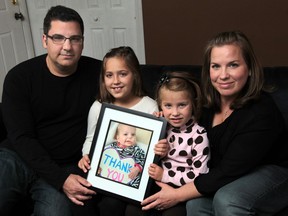 From left,   Tony Pizzuti,  his  daughters Gabby, 9, and Daniella, 5, and wife Jen, display a photo of their late daughter and sister, Emma who pass away from a rare childhood cancer.  The family is extremely grateful to the community for the support they have received.  (JASON KRYK/The Windsor Star)