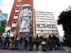 People queue to visit a social housing tower converted into a temporary street art exhibition in Paris, France, Tuesday, Oct. 8, 2013. Condemned apartments never looked so good _ and only rarely has graffiti met such an enthusiastic welcome. More than 80 artists were given free run of a rundown building that is doomed to destruction in 8 days. The line wraps around the block every day to see the apartments, each of which is its own art installation. (Francois Mori/The Associated Press)