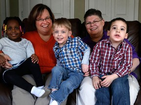 April DeBoer, left, and partner Jayne Rowse, sit with their adopted children Ryanne, 3, Jacob, 3, and Nolan, 4,  at their home in Hazel Park, Mich., on March 5, 2013. The lesbian couple’s desire to adopt each other’s children has grown into a potentially ground-breaking challenge to Michigan’s ban on same-sex marriage. (Paul Sancya/Associated Press)