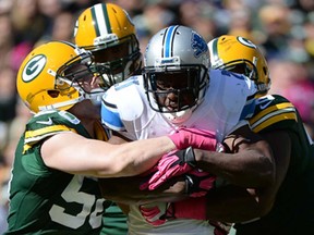 Detroit's Reggie Bush, centre, is wrapped up by A.J. Hawk, right, of the Packers  at Lambeau Field on October 6, 2013 in Green Bay, Wisc. The Lions lost 22-9. (Harry How/Getty Images)