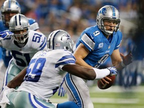 Detroit QB Matthew Stafford, right, tries to outrun the tackle of Dallas' Ernie Sims at Ford Field on October 27, 2013 in Detroit. The Lions won 31-30.( Gregory Shamus/Getty Images)