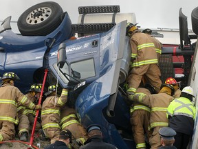 Emergency personnel work to free a truck driver from a roll-over accident Tues. Oct. 29, 2013, on the highway 401 on-ramp at Provincial Rd.  (DAN JANISSE/The Windsor Star)