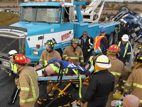 Emergency personnel transport a truck driver from a roll-over accident Tues. Oct. 29, 2013, on the highway 401 on-ramp at Provincial Rd.  (DAN JANISSE/The Windsor Star)