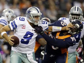 Cowboys quarterback Tony Romo, left, fights off a sack by Denver's Shaun Phillips Sunday, Oct. 6, 2013, in Arlington, Texas. The Broncos won 51-48. (AP Photo/Tony Gutierrez)