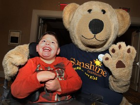 Luca Amaral, 7, of Leamington poses with a Sunshine Foundation mascot Monday, Oct. 21, 2013, at an information session for the DreamLift to Disneyland. He and dozens of other local children with disabilities will be heading to Florida early Tuesday morning for  day of fun.  (DAN JANISSE/The Windsor Star)