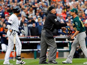 Home plate umpire Gary Darling, centre, stands between Detroit designated hitter Victor Martinez, left, and Oakland relief pitcher Grant Balfour during the ninth inning of Game 3 of an American League baseball division series in Detroit, Monday, Oct. 7, 2013. (AP Photo/Paul Sancya)