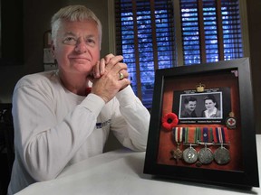 Doug Drouillard poses Friday, Nov. 8, 2013, with a photo of his father Frederick and mother Anastasia Drouillard who both served in the Second World War. (DAN JANISSE/The Windsor Star)