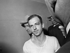 n this Nov. 23, 1963 file photo, Lee Harvey Oswald is led down a corridor of the Dallas police station for another round of questioning in connection with the assassination of U.S, President John F. Kennedy. Oswald, who denied any involvement in the shooting, was formally charged with murder. (AP Photo)